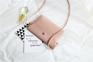 Detail of pink faux leather crossbody bag with lychee texture and gold magnetic buckle