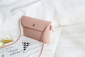 Close-up of pink litchi grain PU leather crossbody bag with golden snap button detail