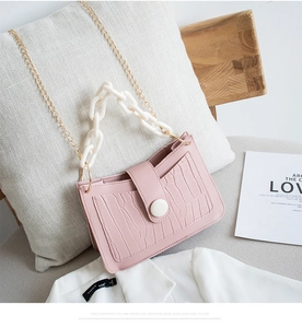 Dettaglio borsa rosa chiaro motivo coccodrillo con catena bianca e tracolla dorata