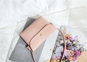 Detailed macro view of pink textured leather phone bag with minimalist gold metal button snap