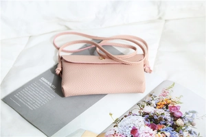Detail of pink lychee texture leather crossbody bag with knot strap and magnetic clasp