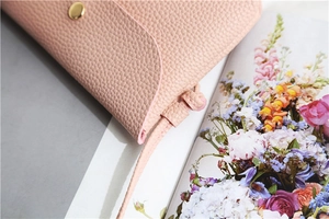 Close-up of pink litchi grain PU leather crossbody bag with golden metal buckle
