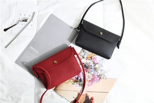 Detail view of mini crossbody bags in black and red pebbled leather with gold metal buckle