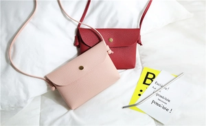 Detail of pink and red pebbled PU leather crossbody bags with golden snap buttons