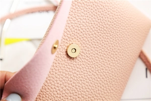 Detail of light pink pebble leather bag with a gold magnetic closure and suede lining