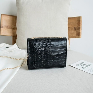 Elegante borsa nera a tracolla effetto coccodrillo con catena dorata in ambiente domestico