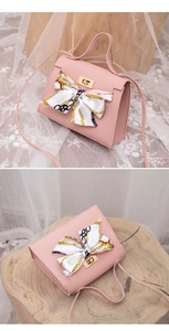 Close-up of pink lychee textured bag with gold twist lock and silk scarf bow detail