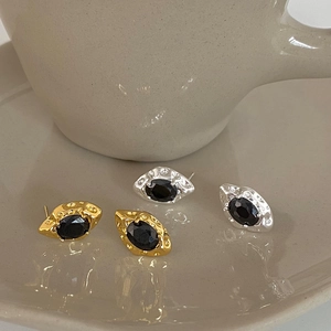 Detail of vintage lava texture gold and silver earrings with oval black zircon stones