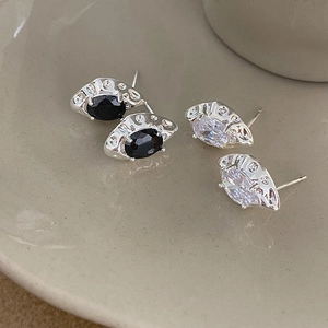 Detailed shot of black and white zircon earrings on a matte ceramic display tray