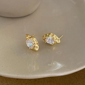 Detail of vintage gold-plated earrings featuring oval clear zircon with hammered metal texture