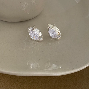 Detail of silver earring with molten metal texture and sparkling round zircon center