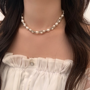 Double-layered pearl and silver twisted metal link necklace worn as a collarbone chain