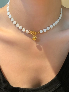 Detail of mother-of-pearl heart bead necklace with golden OT buckle and heart pendant