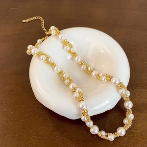 Close-up of double-layer pearl necklace with golden braided chain and lobster clasp