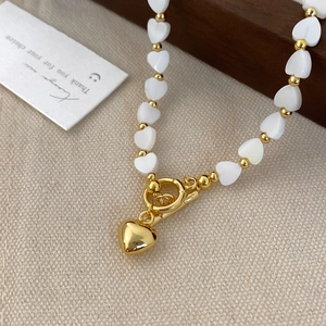 Chic natural mother-of-pearl heart bead necklace with gold-plated toggle clasp on linen