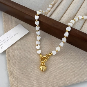 Detailed close-up of natural shell heart beads and gold pendant on a luxury necklace
