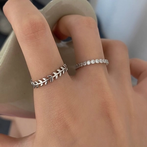 Detail shot of stacked silver leaf texture ring and thin zircon band on model