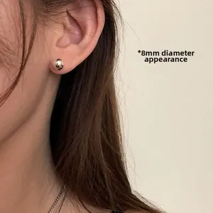 Detail shot of 8mm polished silver ball stud earrings worn by a model for scale