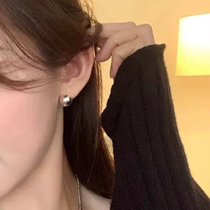 Close-up of a model wearing a polished silver ball stud earring in a minimalist style