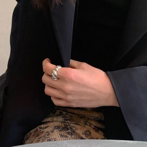 Close-up of a silver croissant-style twisted ring worn on a finger with a stylish suit