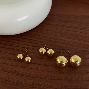 Detailed view of three pairs of minimalist gold-plated ball earrings in different sizes