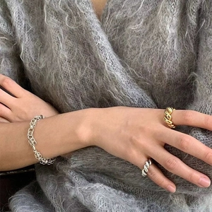Silver link bracelet paired with gold and silver twisted croissant dome rings on a model