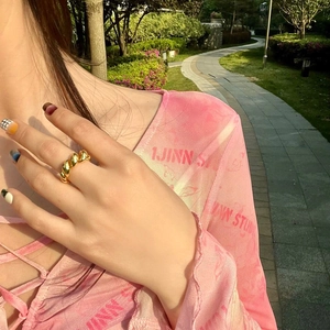 Close-up of gold croissant twisted ring worn by a model in soft outdoor sunlight
