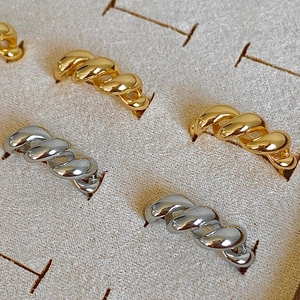 Macro detail of gold and silver croissant twist rings in a velvet display box