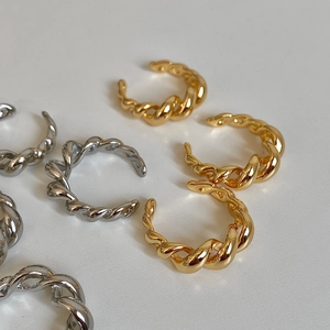 Detail of twisted croissant rings in gold and silver finish with braided texture