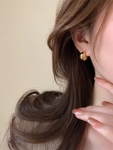 Close-up of elegant gold thick hoop earrings with a high-polish finish on model
