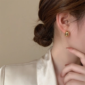 Close-up of elegant gold geometric stud earrings with a polished mirror finish on model