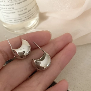 Close-up of minimalist silver water drop stud earrings with high-polish metallic finish