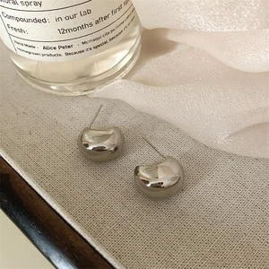Detailed view of silver minimalist C-shaped hoop earrings on elegant silk fabric