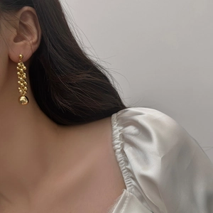 Detail view of golden cluster spherical drop earrings worn by a model in soft lighting