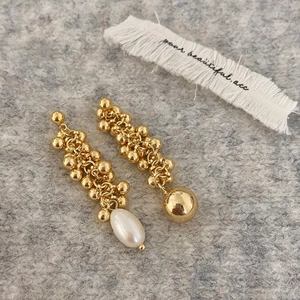 Detail of asymmetric gold ball chain earrings featuring a white freshwater pearl drop