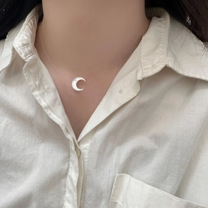 Minimalist shell crescent moon necklace with invisible chain worn on a female model