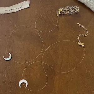Detailed shot of crescent moon shell pendant on invisible nylon cord with gold lobster clasp