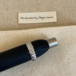 Macro d'une bague tressée en argent avec pavé de zircons sur fond de tissu texturé