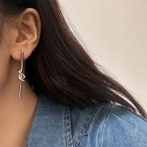 Primo piano di orecchini minimalisti in argento con nappe e design a nodo sulla modella