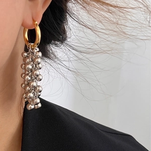 Close-up of elegant gold and silver metal cluster tassel earrings worn by a model