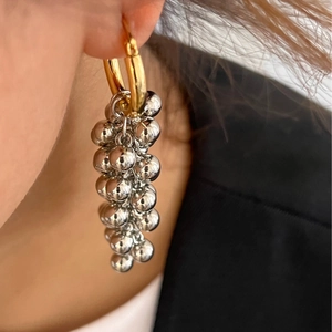 Close-up of elegant gold hoop earrings with cascading silver metallic bead clusters