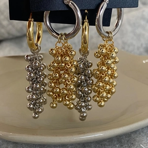 Close-up of gold and silver metallic beaded tassel earrings hanging on display card