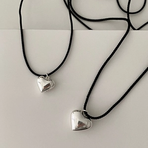 Detailed view of large and small puffy heart pendants on black woven cord necklaces