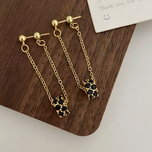 Macro detail of gold tassel earrings with black pavé zircon pendants on wooden background