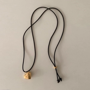 Detail of adjustable black woven cord with gold heart pendant and polished beads