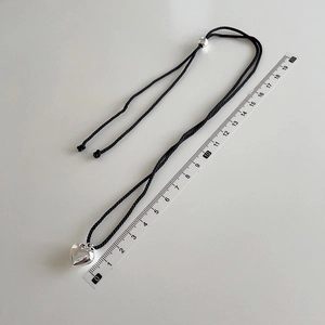 Close-up of polished silver heart pendant with black braided rope and size measurement