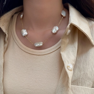 Detailed view of Baroque freshwater pearls on a gold chain worn on a woman's neck