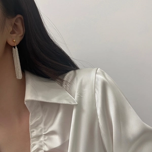 Detail of long fringe earrings with gold studs and silver chain tassels on model