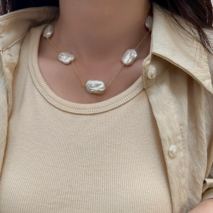 Detailed view of Baroque freshwater pearl necklace with gold chain worn by a model