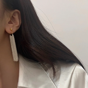 Elegant long fringe tassel earrings in gold and silver finish worn by a model